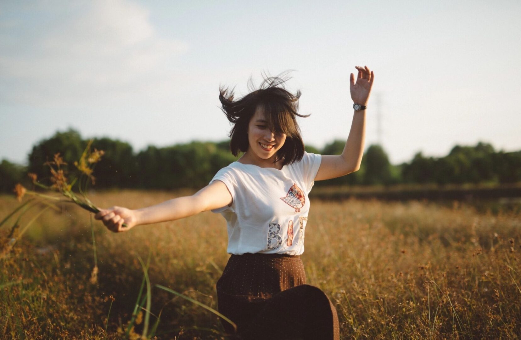 A woman in the middle of a field with her arms outstretched.